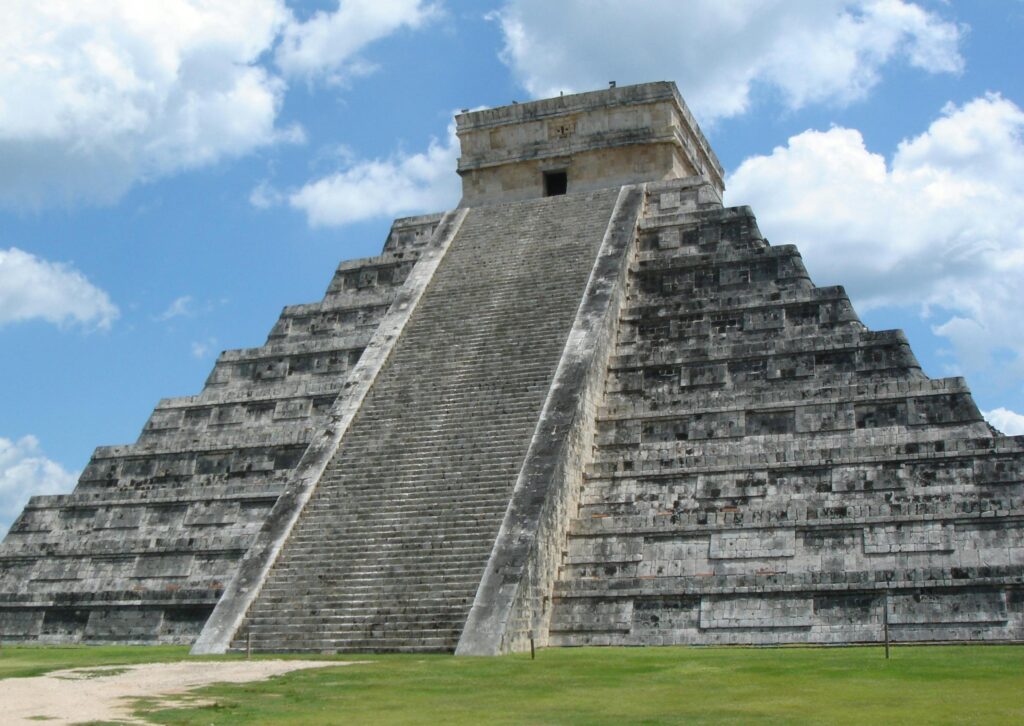 Stunning view of El Castillo pyramid at Chichen Itza under a blue sky with clouds.